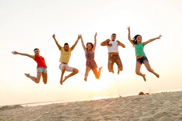 Amigos sonrientes bailando y saltando en la playa —  Fotos de Stock