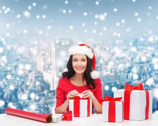 Lachende vrouw in santa helper hoeden verpakking geschenken — Stockfoto