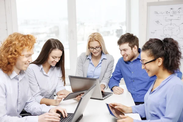 Equipe sorridente com laptop e mesa pc computadores — Fotografia de Stock