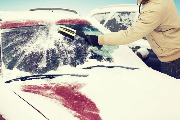 Hombre limpiando nieve del parabrisas del coche con cepillo —  Fotos de Stock