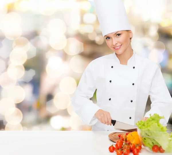 Glimlachend vrouwelijke chef-kok hakken groenten — Stockfoto