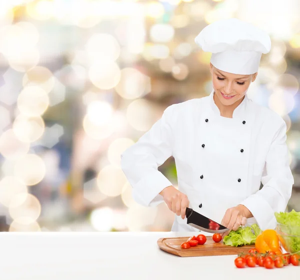 Sorridente chef feminino cortar legumes — Fotografia de Stock
