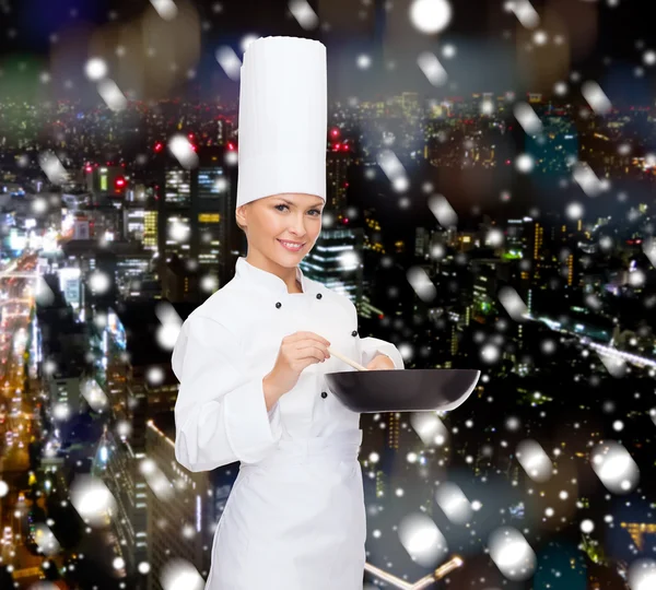 Lachende vrouwelijke chef-kok met pan- en -lepel — Stockfoto