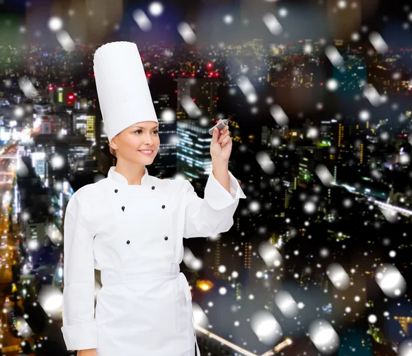 Smiling female chef writing something on air — Stock Photo, Image