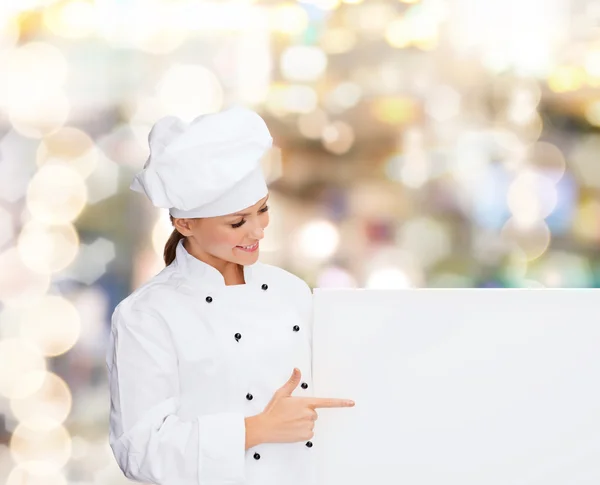 Smiling female chef with white blank board — Stock fotografie