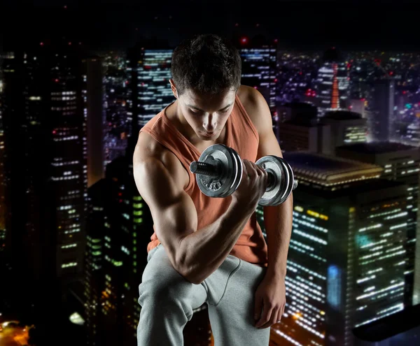 Jovem com bíceps de flexão de halteres — Fotografia de Stock