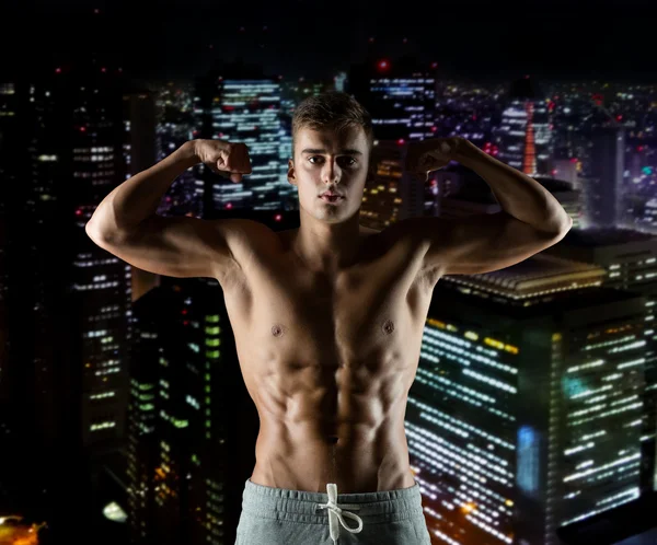 Young man showing biceps and muscles — Stock Photo, Image