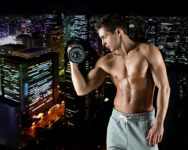 Young man with dumbbell flexing biceps — Stock Photo, Image