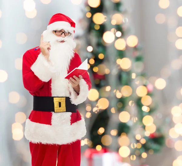 Homem em traje de santa claus com bloco de notas — Fotografia de Stock