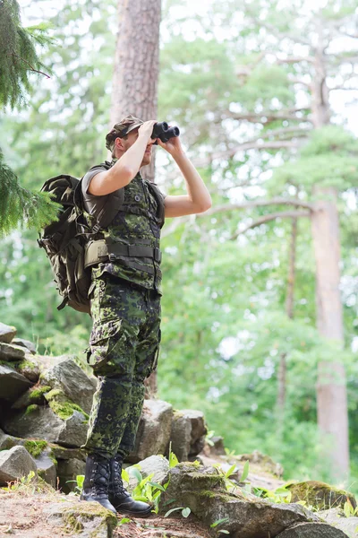 双筒望远镜和背包在森林里的士兵 — 图库照片
