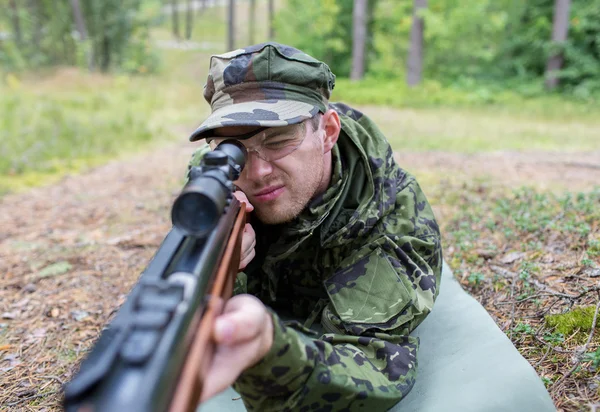 Close up of soldier or hunter with gun in forest — Stock Photo, Image