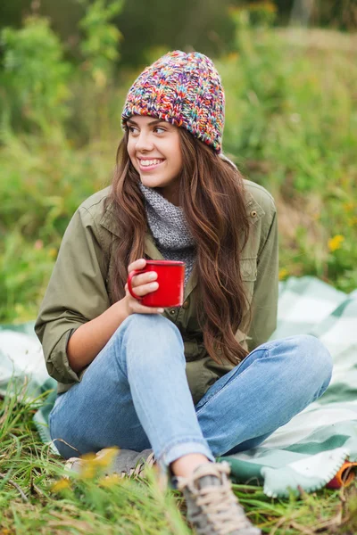 Smiling young woman with cup sitting in camping — Stock Photo, Image