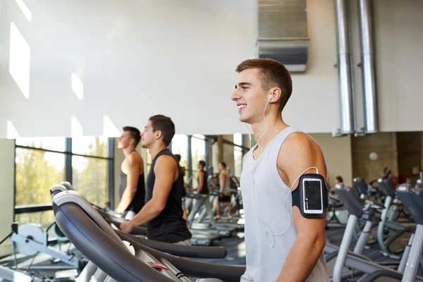 Hombre con smartphone haciendo ejercicio en la cinta de correr en el gimnasio — Foto de Stock