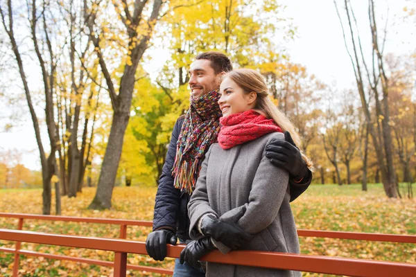Pareja sonriente abrazándose en el puente en el parque de otoño — Foto de Stock