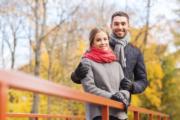 Улыбающаяся пара обнимается на мосту в осеннем парке — стоковое фото