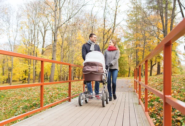 Mosolygó pár baba babakocsi őszi parkban — Stock Fotó