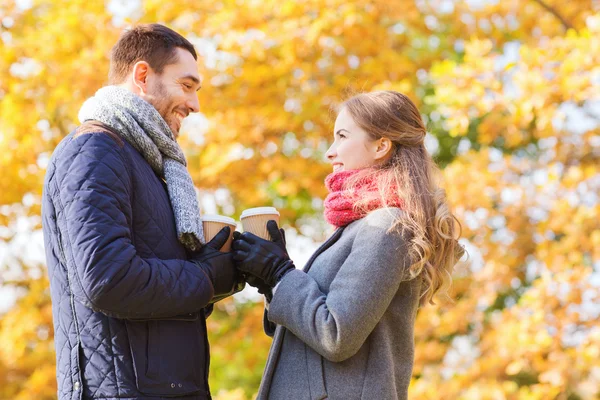 Coppia sorridente con tazze di caffè nel parco autunnale — Foto Stock