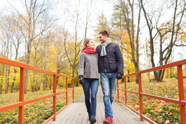 Lächelndes Paar umarmt sich auf Brücke im Herbstpark — Stockfoto