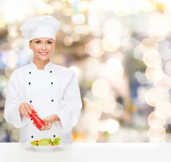 Glimlachend vrouwelijke chef-kok verfraaien plantaardige salade — Stockfoto