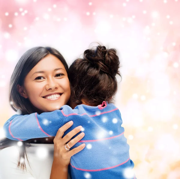 Sonriente niña y madre abrazándose en el interior — Foto de Stock