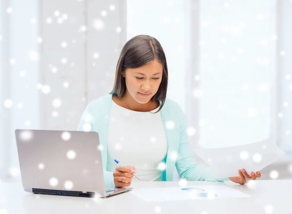 Lächelnde junge Frau mit Laptop und Papieren — Stockfoto