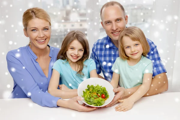 Happy family with two kids showing salad in bowl — Stock Photo, Image