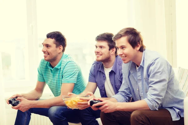 Улыбающиеся друзья, играющие в видеоигры дома — стоковое фото
