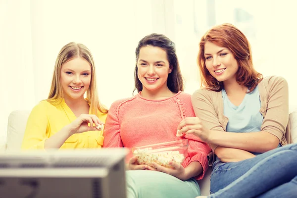 Tre leende tonårig flicka tittar på tv hemma — Stockfoto