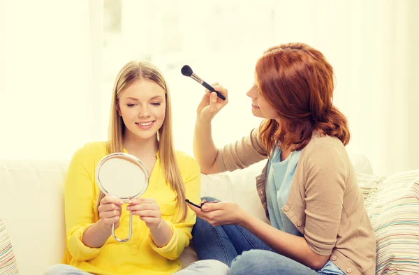 Two smiling teenage girls applying make up at home — Stock Photo, Image