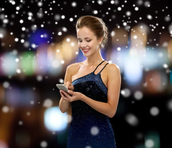 Femme souriante en robe de soirée avec smartphone — Photo