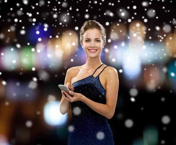 Усміхнена жінка в вечірній сукні зі смартфоном — стокове фото