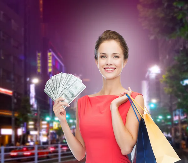 Mujer sonriente con bolsas de compras y dinero —  Fotos de Stock
