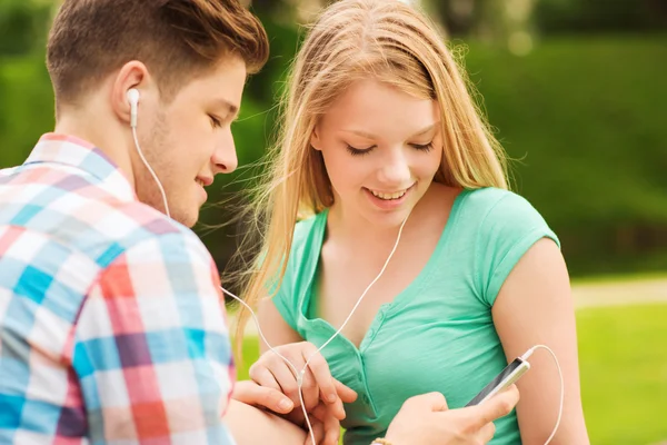 Smiling couple with smartphone and earphones — Stock Photo, Image