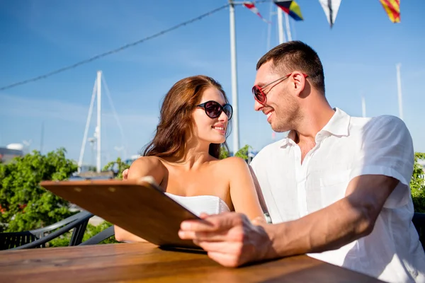 Smiling couple with menu at cafe — Stock Photo, Image