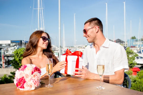 Lächelndes Paar mit Geschenkbox-Café — Stockfoto