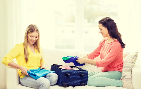 Duas meninas adolescentes sorridentes que embalam mala em casa Imagens De Bancos De Imagens