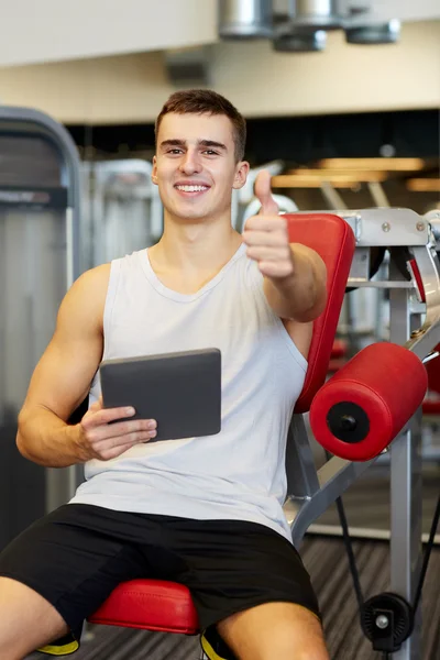Улыбающийся молодой человек с планшетным компьютером в тренажерном зале — стоковое фото