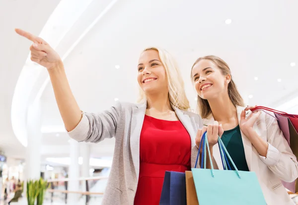 Mujeres jóvenes felices con bolsas de compras en el centro comercial —  Fotos de Stock