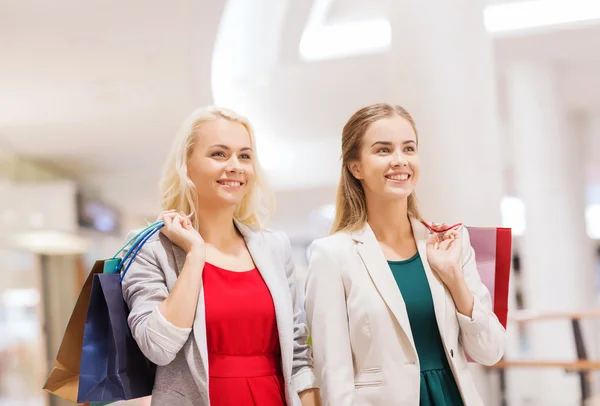 Gelukkig jonge vrouwen met boodschappentassen in winkelcentrum — Stockfoto