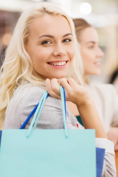 Happy young women with shopping bags in mall — Stock Photo, Image