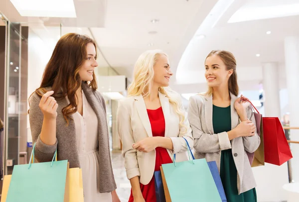 Mujeres jóvenes felices con bolsas de compras en el centro comercial — Foto de Stock