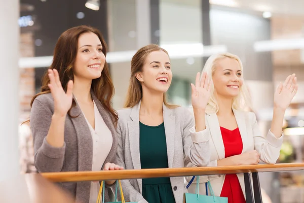 Gelukkig jonge vrouwen met boodschappentassen in winkelcentrum — Stockfoto