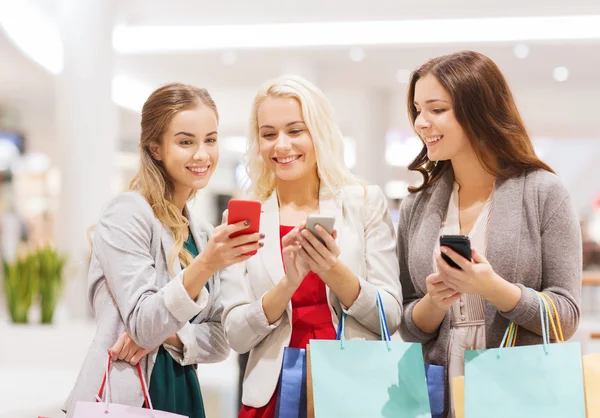 Mujeres felices con teléfonos inteligentes y bolsas de compras — Foto de Stock