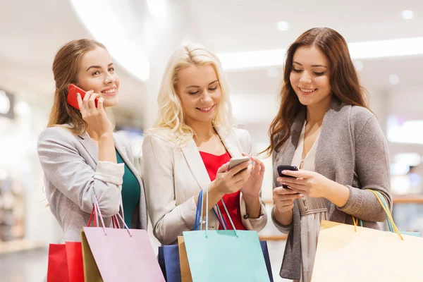 Mujeres felices con teléfonos inteligentes y bolsas de compras —  Fotos de Stock