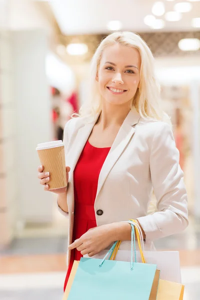 Jonge vrouw met shopping tassen en koffie in winkelcentrum — Stockfoto