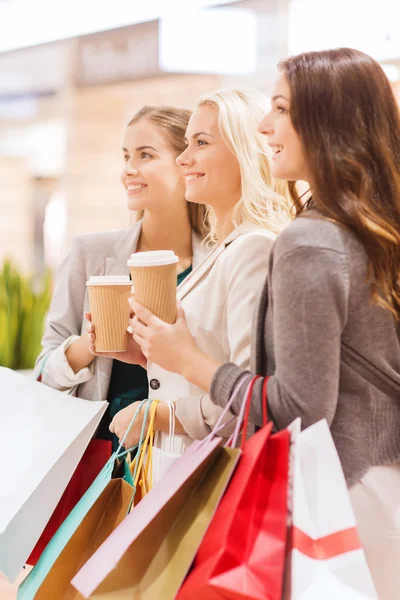 Mulheres jovens com sacos de compras e café no shopping — Fotografia de Stock