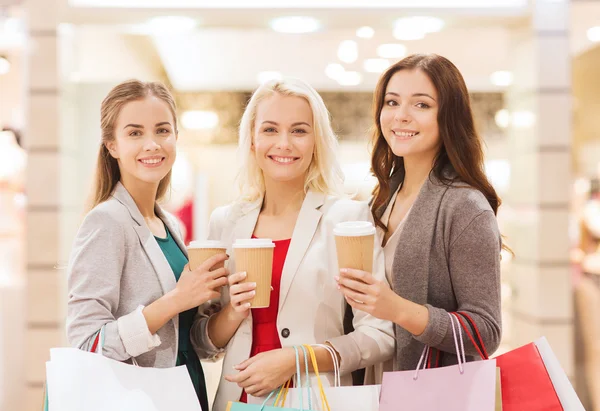 Unga kvinnor med påsar och kaffe i mall — Stockfoto