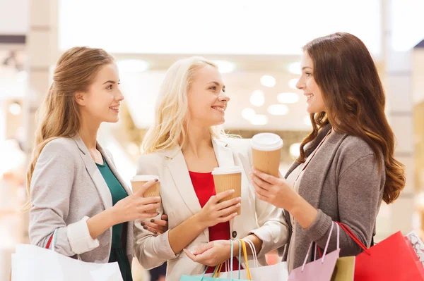 Jonge vrouwen met shopping tassen en koffie in winkelcentrum — Stockfoto