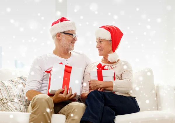 Glückliches Seniorenpaar in Weihnachtsmützen mit Geschenkschachteln — Stockfoto