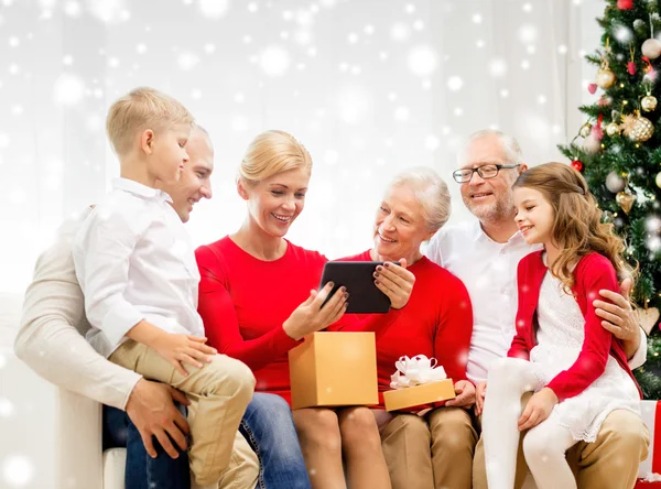 Familia sonriente con tablet pc y caja de regalo en casa — Foto de Stock